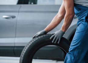 Art of transportation. Mechanic holding a tire at the repair garage. Replacement of winter and summer tires.